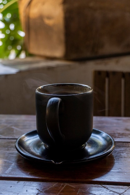 Foto taza de café con arcilla negra vegetación de mesa de madera en el fondo y flores