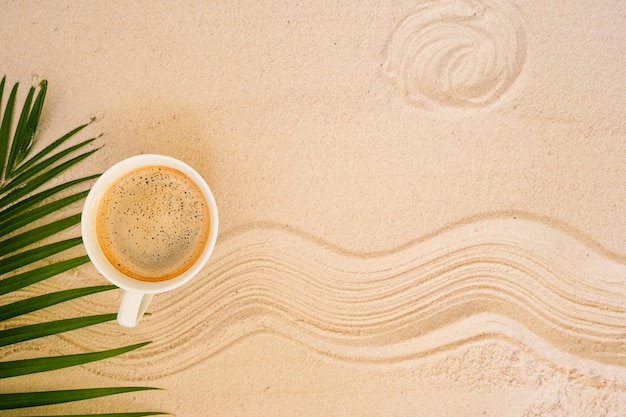 Taza de café en la arena con onda y patrón de sol Fondo de verano