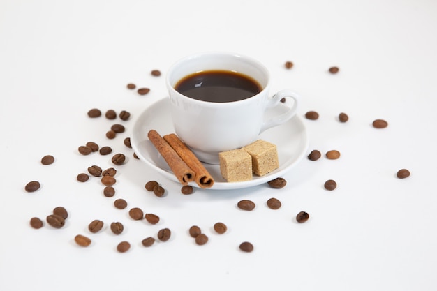 Taza de café aromático con canela y granos de café.