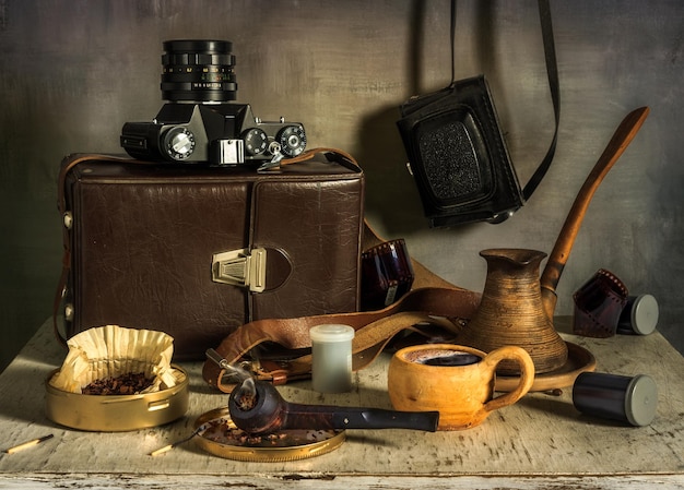 Una taza de café aromático Una pipa para fumar y una caja de tabaco Cámaras de película antiguas película fotográfica