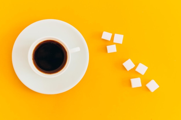 Taza de café con azúcar blanco sobre fondo amarillo