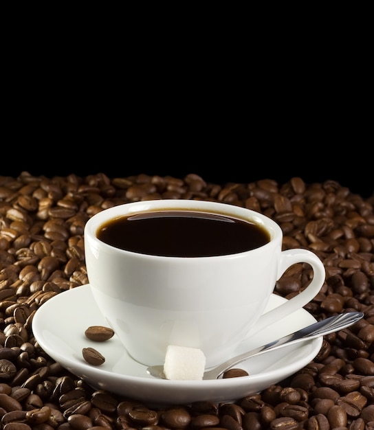 Taza de café y azúcar en frijoles aislados en negro