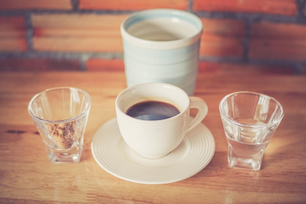 Taza de café con azúcar marrón y agua en la mesa