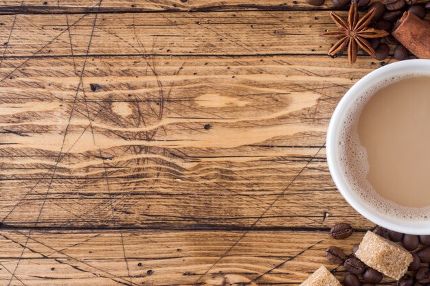 Taza de café, azúcar moreno y canela con anís en madera.