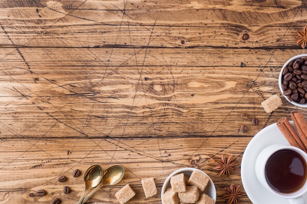 Foto taza de café, azúcar moreno y canela con anís sobre madera.