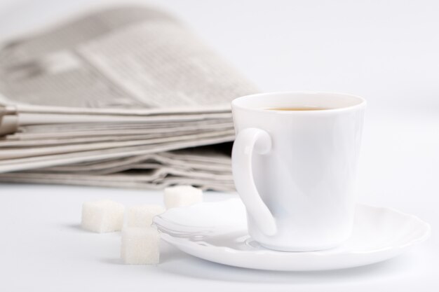 Taza de café, azúcar y pila de periódicos closeup