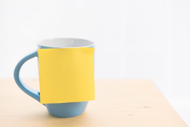 Taza de café azul y post-it en la mesa de madera