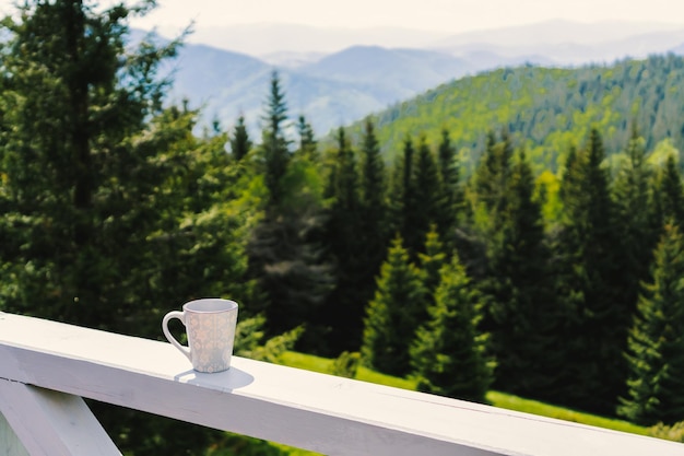 Una taza de café en el balcón con el telón de fondo de montañas y bosques verdes. montes de Cárpatos