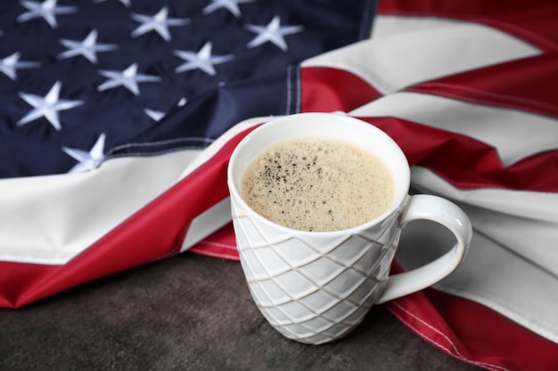 Taza de café y bandera estadounidense sobre fondo gris