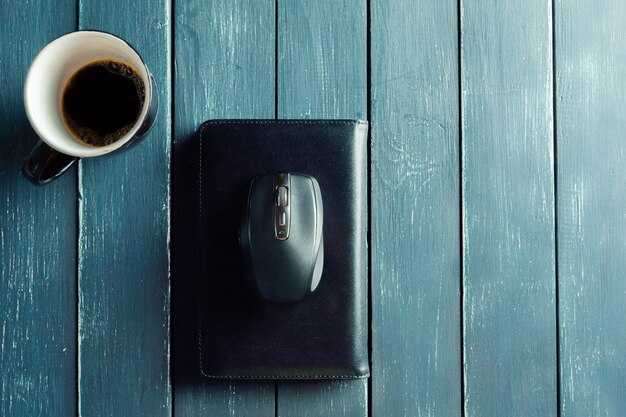 Taza de café, billetera y mouse sobre mesa de madera oscura