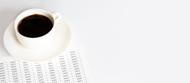 Una taza de café blanca junto a los documentos. Un descanso con una taza de café en el trabajo, negocios
