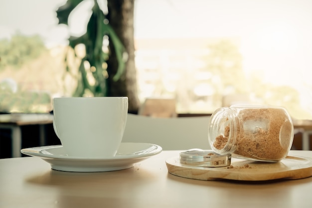 Taza de café blanco caliente en la mesa de madera sobre fondo verde