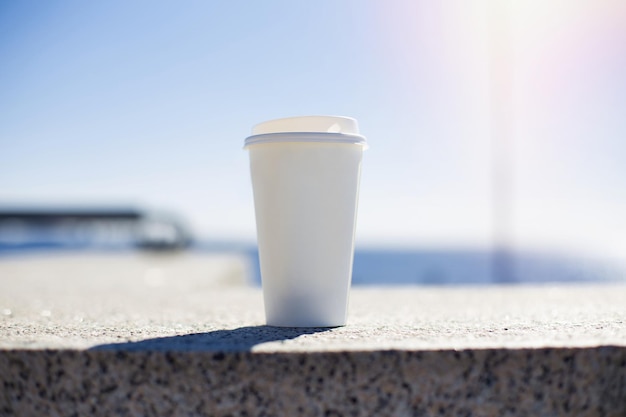 Taza de café blanco en el fondo del mar al atardecer