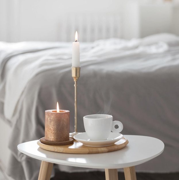 Taza de café blanco con velas en la mesa interior