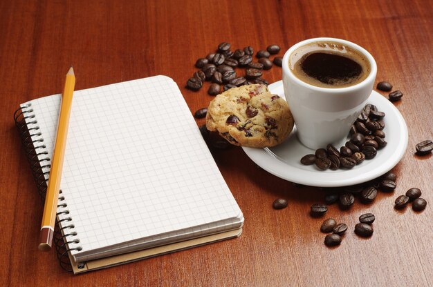 Taza de café y el bloc de notas abierto en la mesa