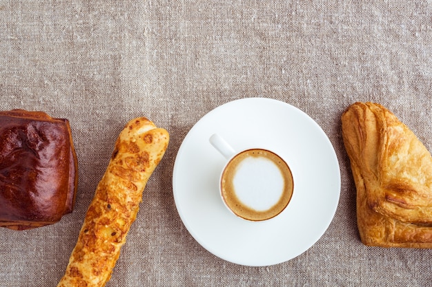 Una taza de café y bollos alineados en una fila. Vista superior de estilo plano.