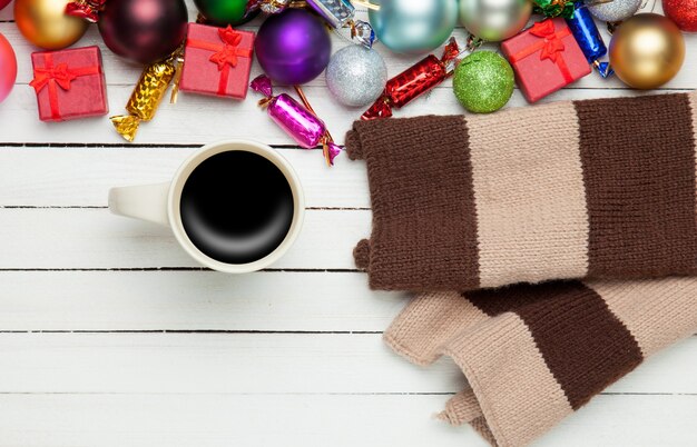 Taza de café y bufanda con juguetes navideños.