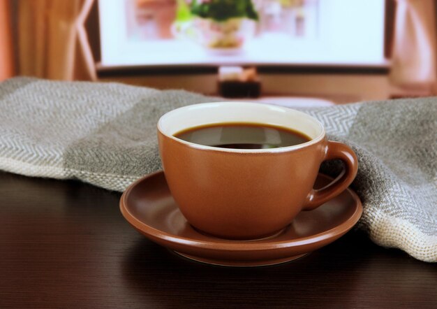 Taza de café con bufanda en la mesa en la habitación