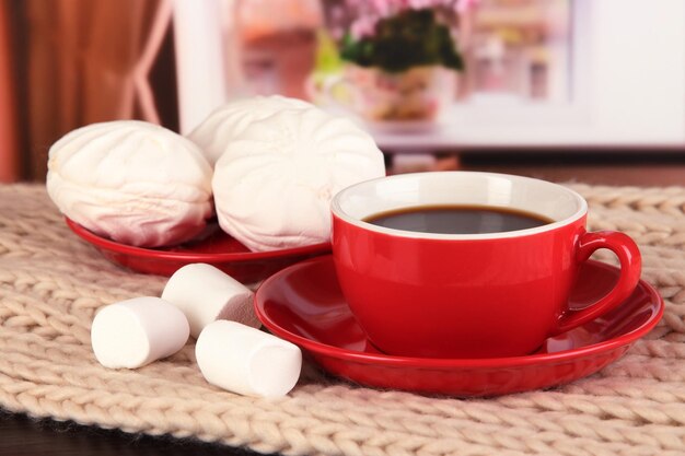 Taza de café con bufanda en la mesa en la habitación