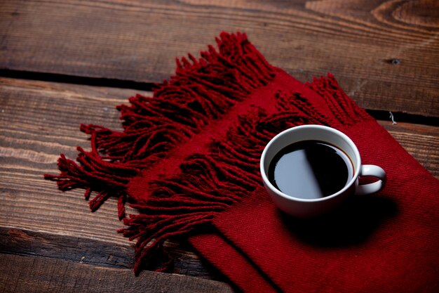 Taza de café y bufanda en mesa de madera