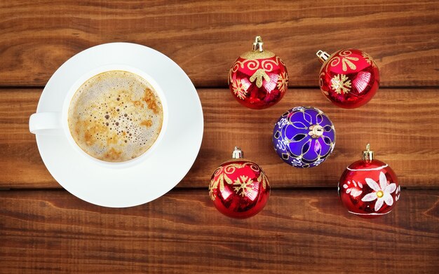 Taza de café y burbujas navideñas sobre fondo de madera.