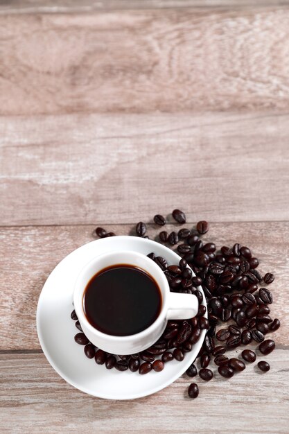 Taza de café y café en grano en el escritorio de madera