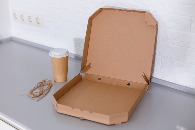 Taza de café y caja de pizza sobre fondo blanco.