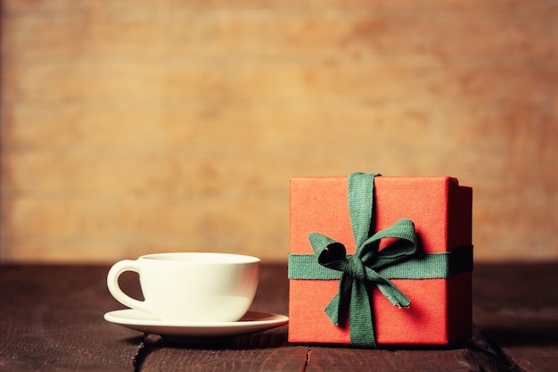 Taza de café y caja de regalo en mesa de madera.