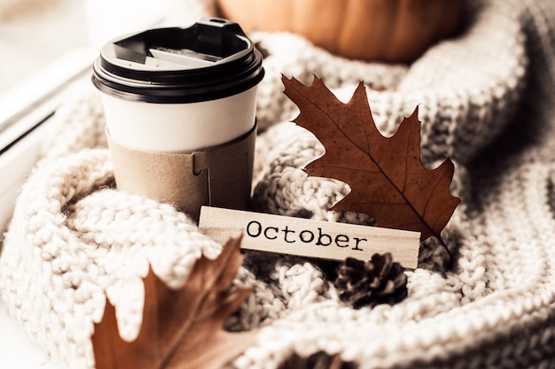 Foto taza de café, calabaza, hojas secas de otoño en la ventana.