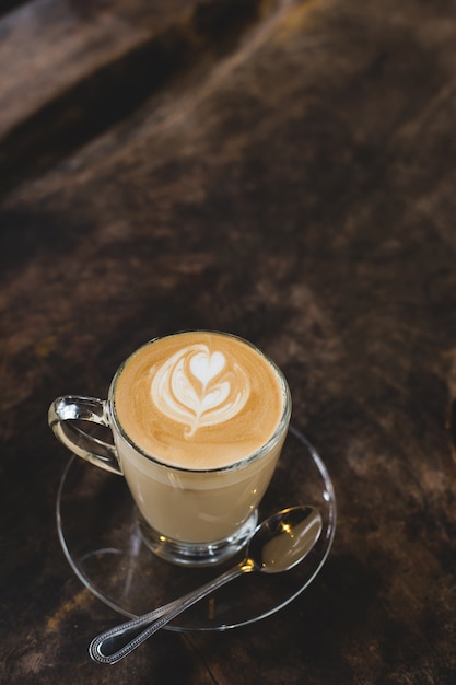 Taza de café caliente arte latte en la mesa de madera