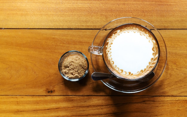 Taza de café caliente con azúcar de caña en la mesa de madera