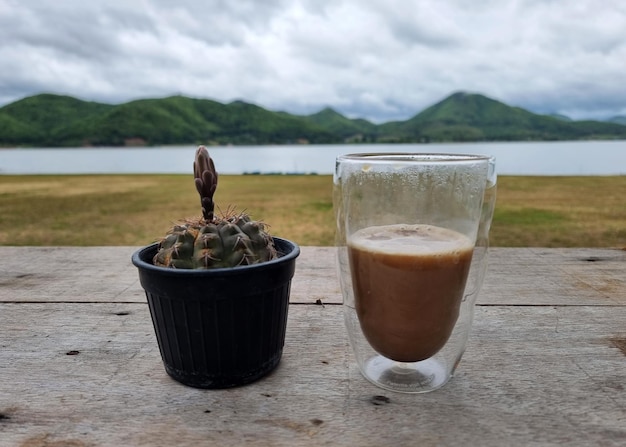 Una taza de café caliente con un cactus en el fondo borroso de una montaña y el embalse