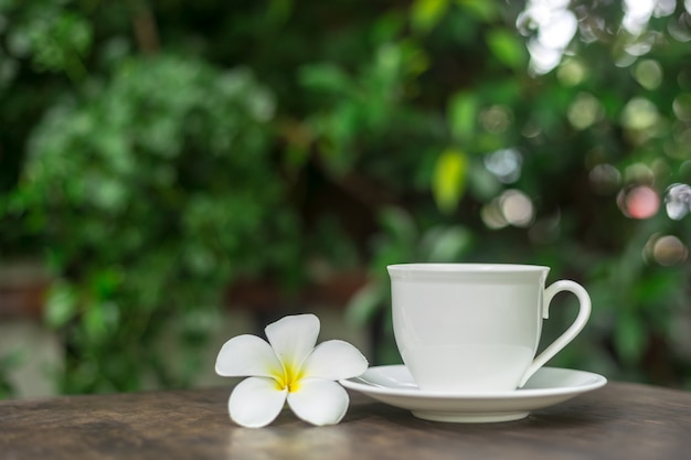 Taza de café caliente con decoración de flores blancas en la mesa