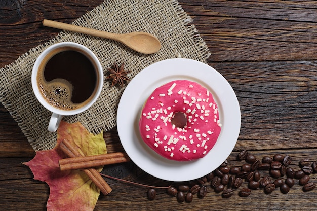 Taza de café caliente con donut dulce para el desayuno en la mesa de madera antigua, vista superior