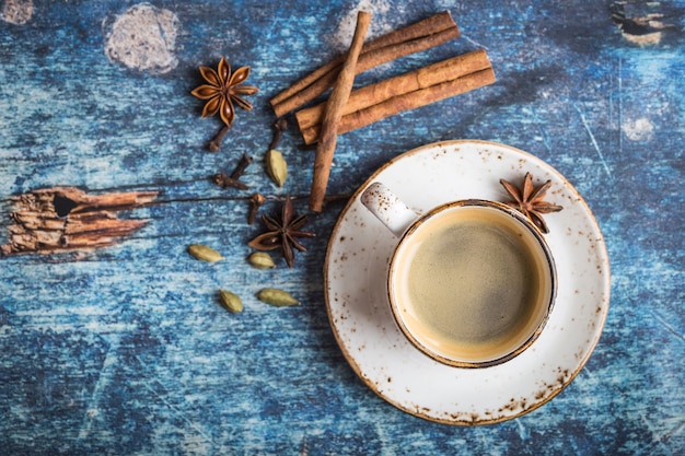 Taza de café caliente con especias en la vieja mesa de madera azul rústica