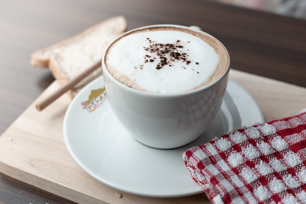 Taza de café caliente y espuma de leche en la cafetería.