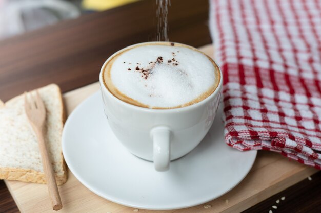 Foto taza de café caliente y espuma de leche en la cafetería.