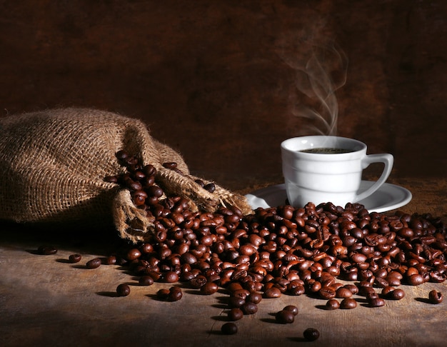 Taza de café caliente y frijoles sobre un fondo oscuro