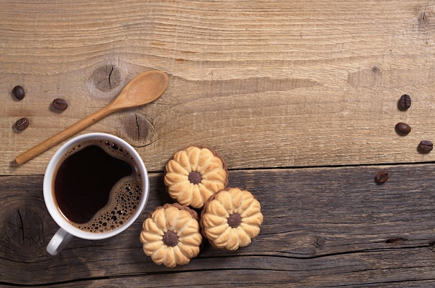 Taza de café caliente y galletas con chocolate para el desayuno en la mesa de madera vieja, vista superior. Espacio para texto