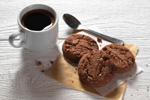 Taza de café caliente con galletas de chocolate en la mesa de madera blanca