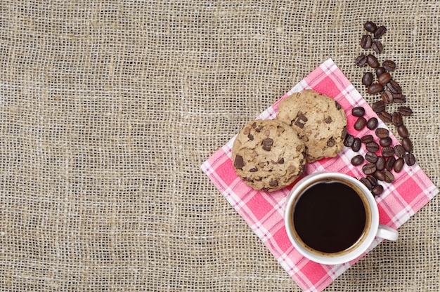 Taza de café caliente con galletas de chocolate sobre un fondo de arpillera, vista superior