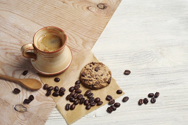 Taza de café caliente con galletas de chocolate sobre fondo de madera