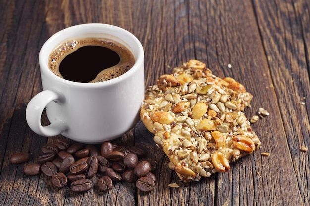 Taza de café caliente y galletas con diferentes nueces en una mesa de madera vintage