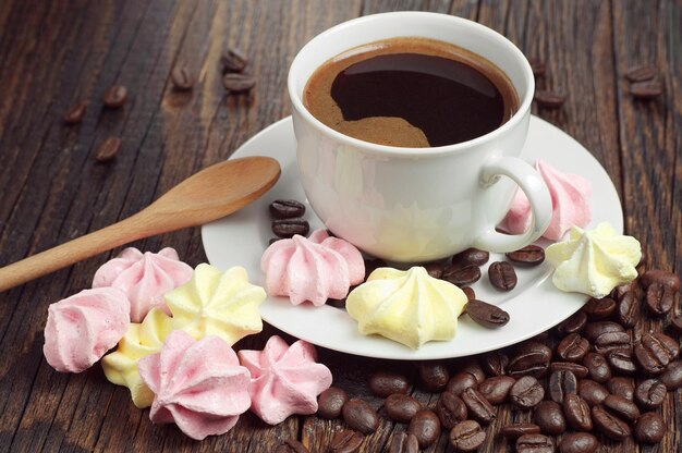 Taza de café caliente con galletas de merengue en la mesa de madera oscura