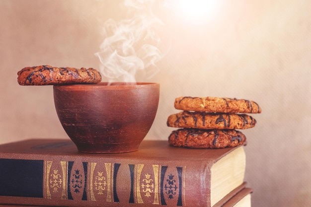 Taza de café caliente y galletas en una pila de libros