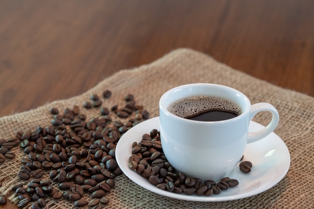 Taza de café caliente con granos de café tostados.