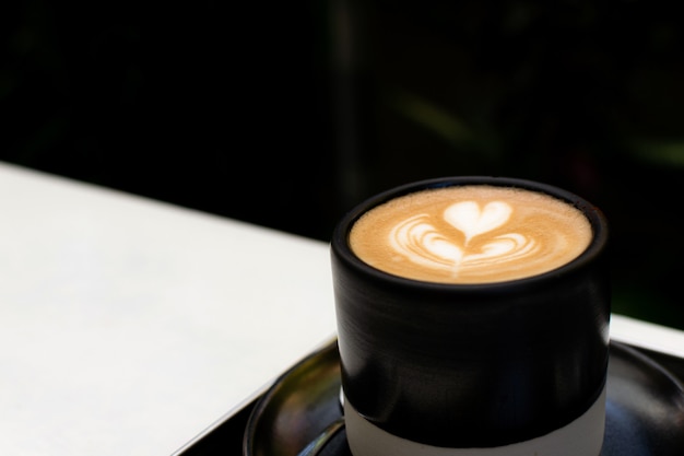 Taza de café caliente con hermoso arte latte en la mesa.