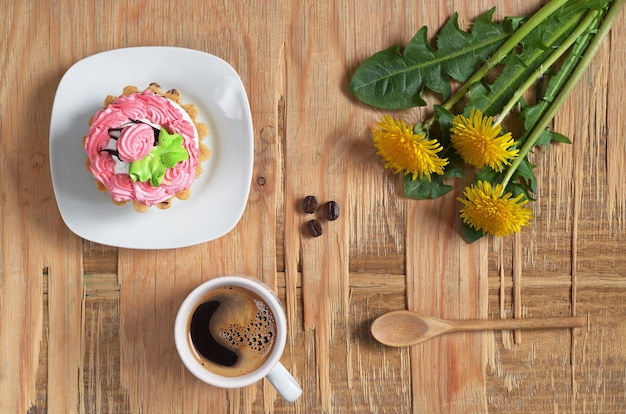 Taza de café caliente, pastel dulce y flores sobre fondo de madera vieja, vista superior