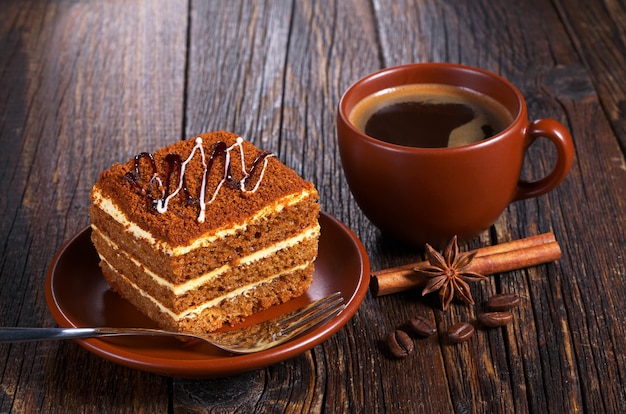 Taza de café caliente y pastel de miel en la mesa de madera oscura.