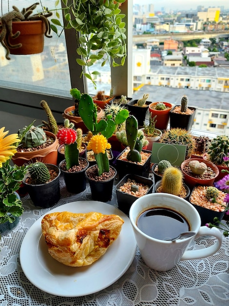 Una taza de café caliente con pastel de pollo sobre fondo de cactus y suculentas